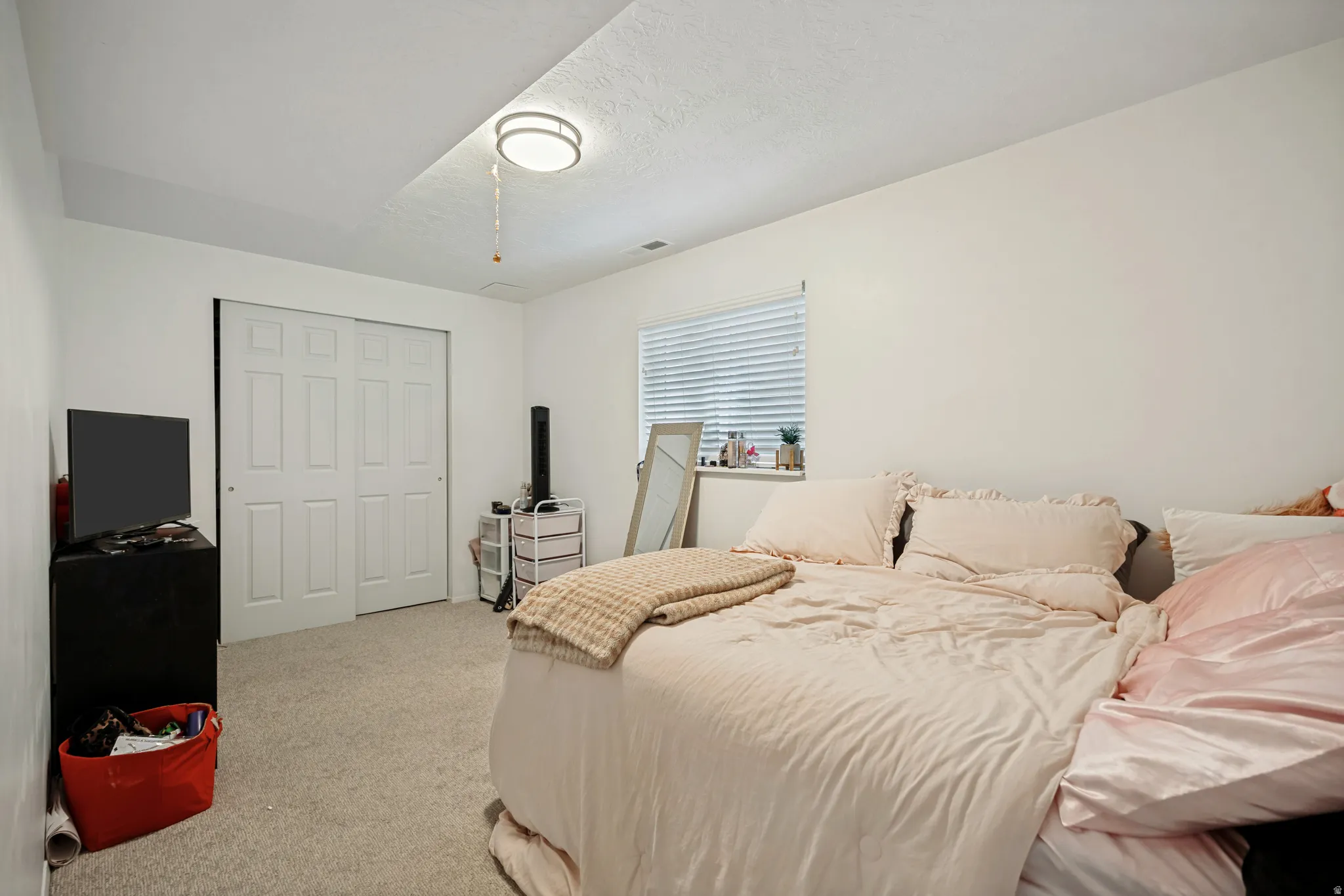 6711 - Basement Bedroom 2. White paneled bi-fold closet doors, light-colored carpet flooring, recessed window, and flush-mount ceiling light fixture