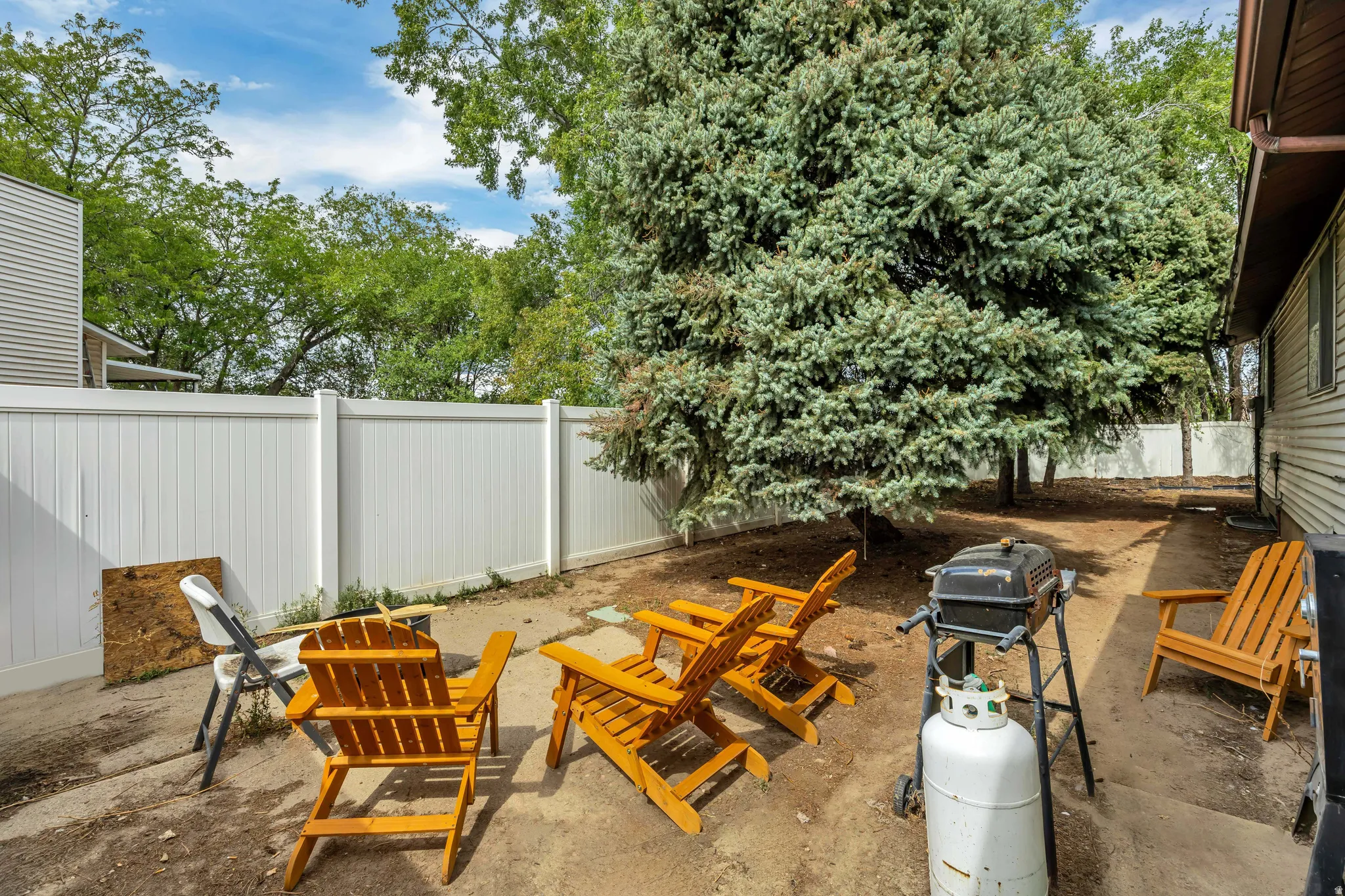 6709 - Enclosed outdoor area featuring a white privacy fence and mature evergreen trees