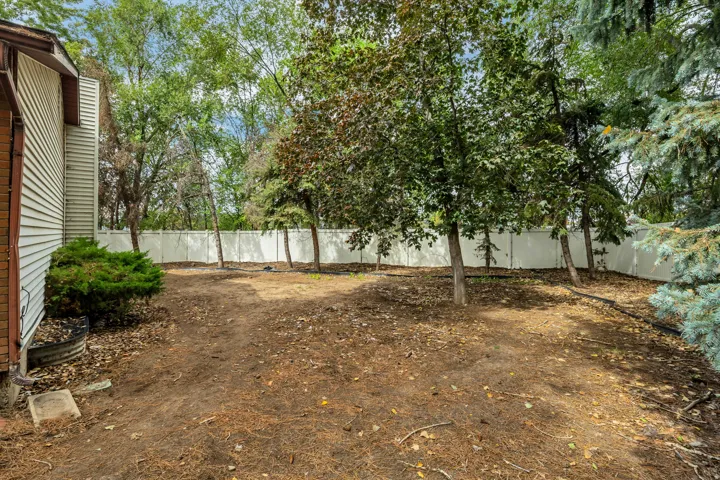 6709 - Fenced backyard featuring mature trees, a privacy fence, and an expansive ground area