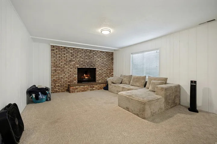 6711 - Basement Living Room. Brick-surround fireplace with hearth, white paneled walls, and recessed lighting