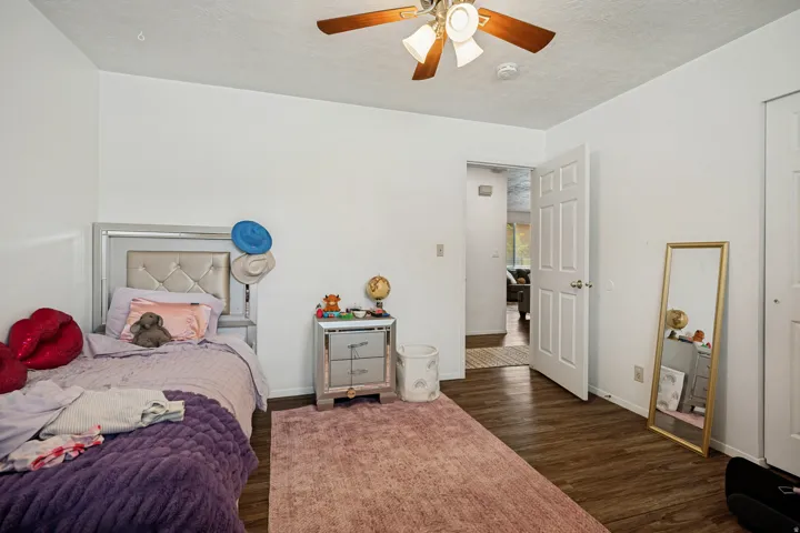 6711 - Main level bedroom 2. Wood-finish flooring, white walls, and a ceiling fan with integrated lighting