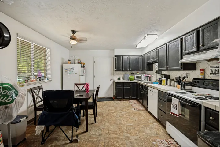 6709 - Kitchen featuring black cabinetry, white countertops, tile backsplash, and a ceiling fan