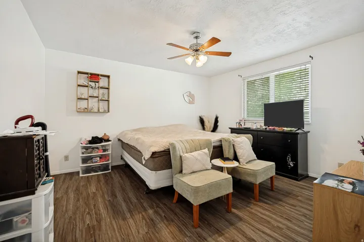 6711 - Main Level Bedroom1. Wood-finish flooring, ceiling fan, white walls, and a window with blinds