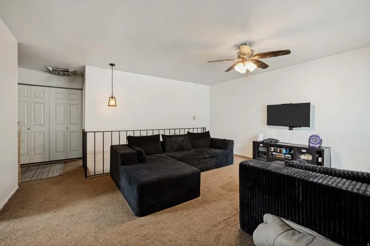 6709 -Main level living room. Neutral wall finishes, carpet flooring, a ceiling fan with integrated lighting, and a pendant light fixture