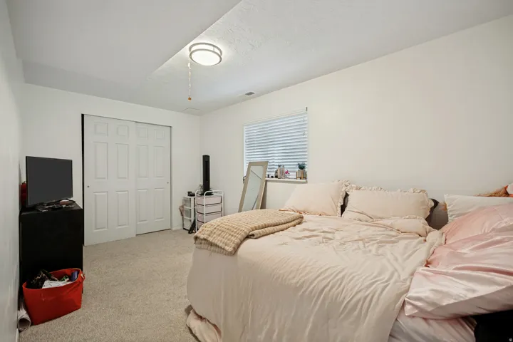6711 - Basement Bedroom 2. White paneled bi-fold closet doors, light-colored carpet flooring, recessed window, and flush-mount ceiling light fixture