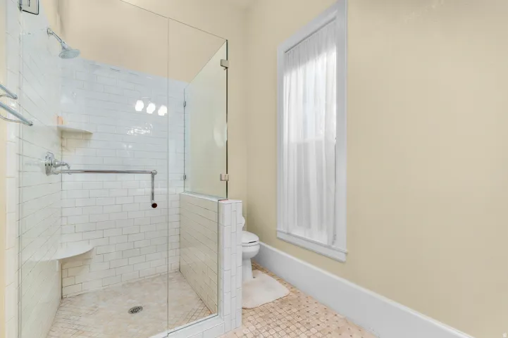 Glass-enclosed shower with subway tile surround, integrated shower bench, and polished chrome fixtures