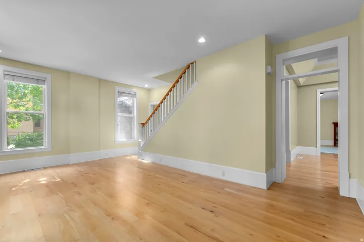 Hardwood flooring throughout, multiple windows, recessed lighting, and a prominent staircase with wood handrails