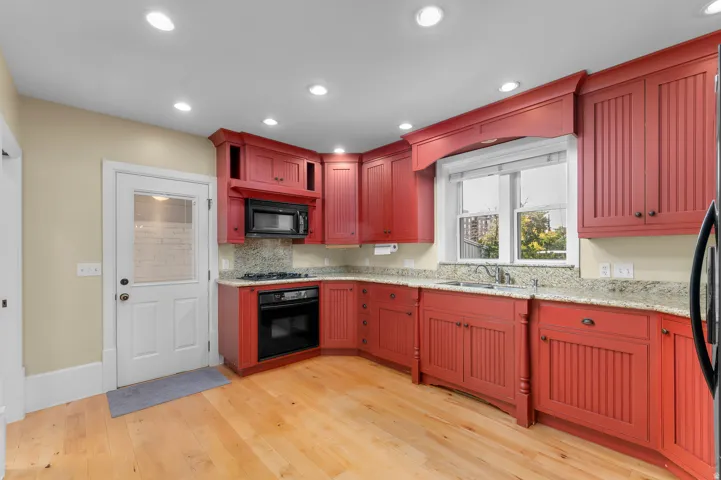 Kitchen featuring red cabinetry, light wood-finish flooring, recessed lighting, and light-toned countertops with a matching backsplash
