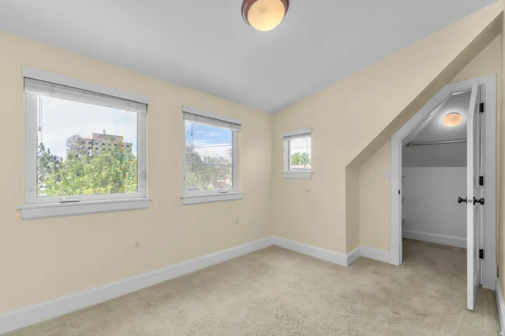 Textured carpeting, multiple windows, built-in closet with hanging rod, and ceiling-mounted light fixtures