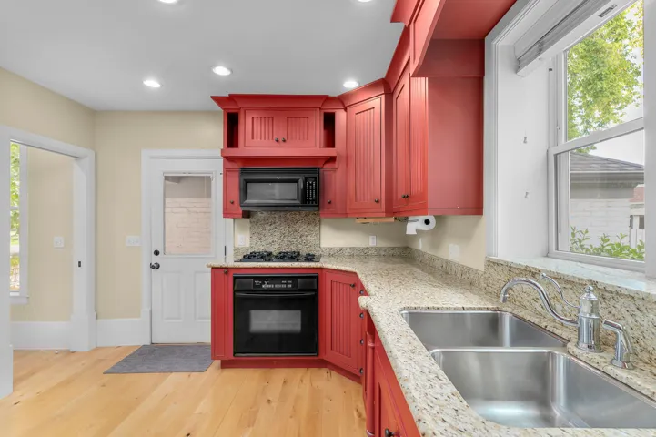 Kitchen featuring red cabinetry, granite-finish countertops, and wood-finish flooring