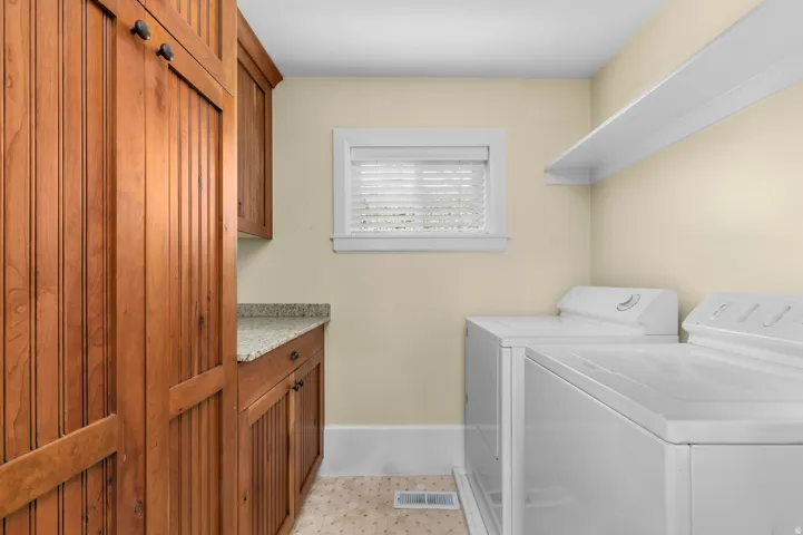 Built-in wood cabinetry with beadboard paneling, granite-look countertop, and a window with blinds