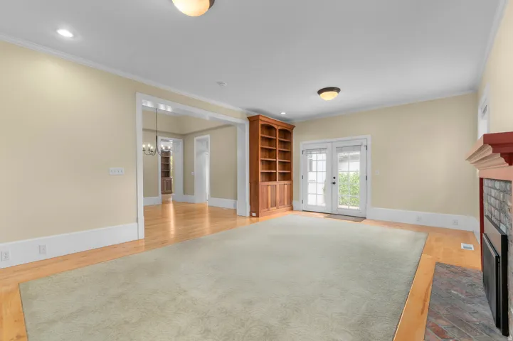 Hardwood flooring, built-in shelving, a fireplace with a stone surround, and double French doors to the exterior