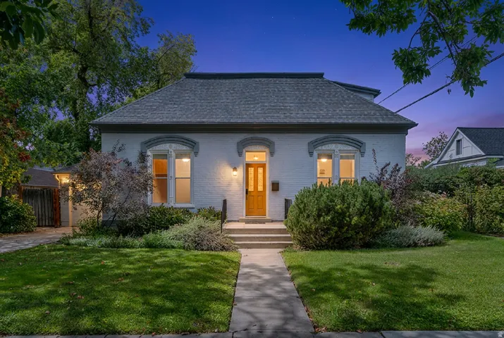 Brick exterior, gambrel roof, mature landscaping, paved walkway, and a wooden front door