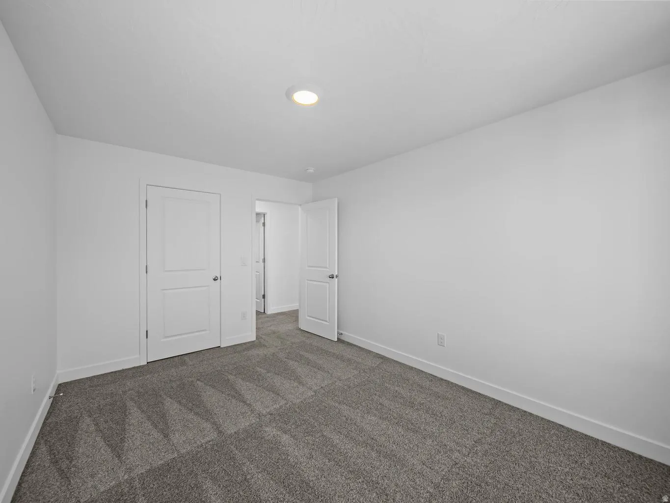 Recessed ceiling lighting, patterned carpet, white interior doors, and crisp white walls