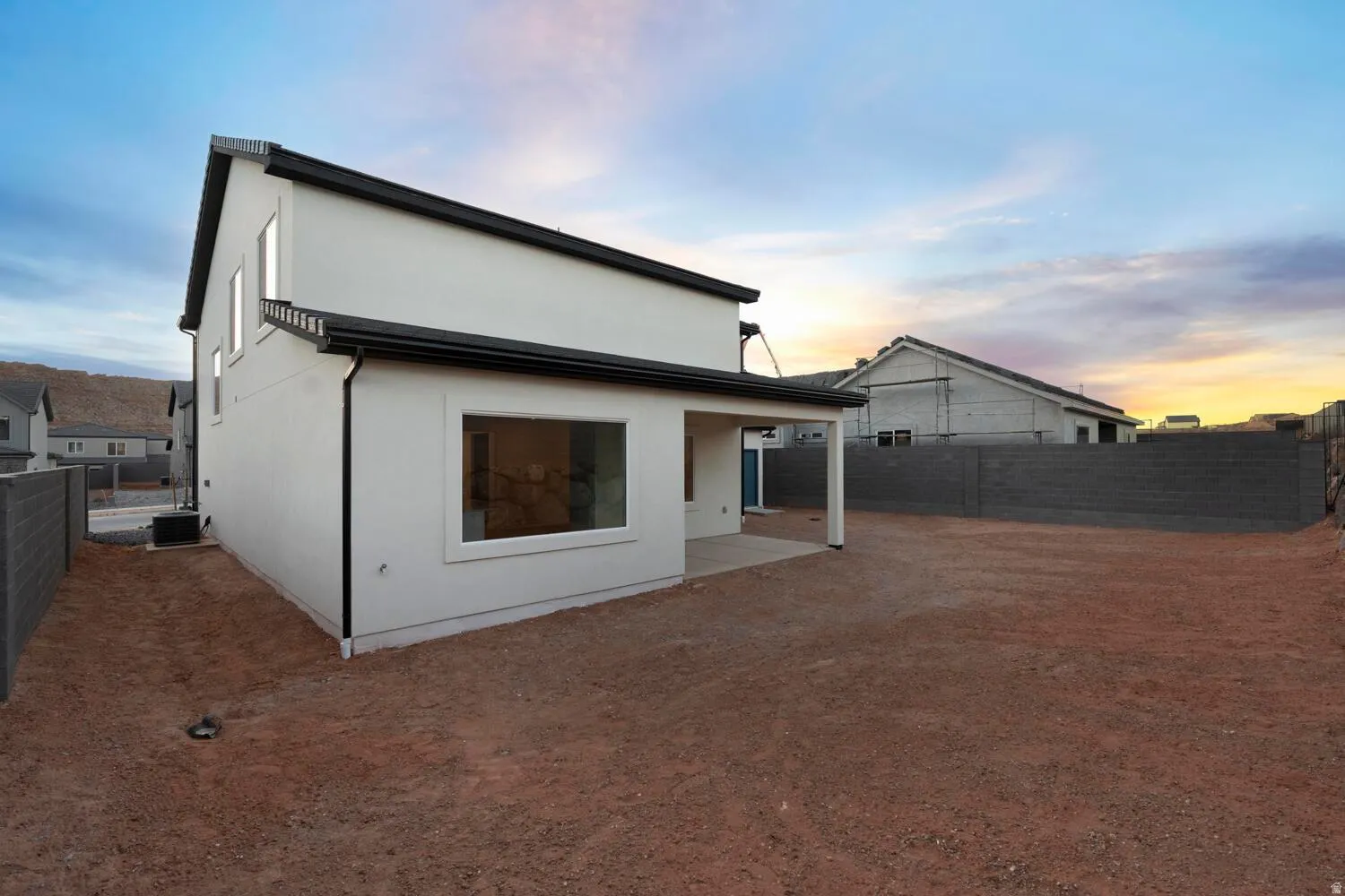 Rear exterior featuring a covered patio, multiple windows, and a partially enclosed yard