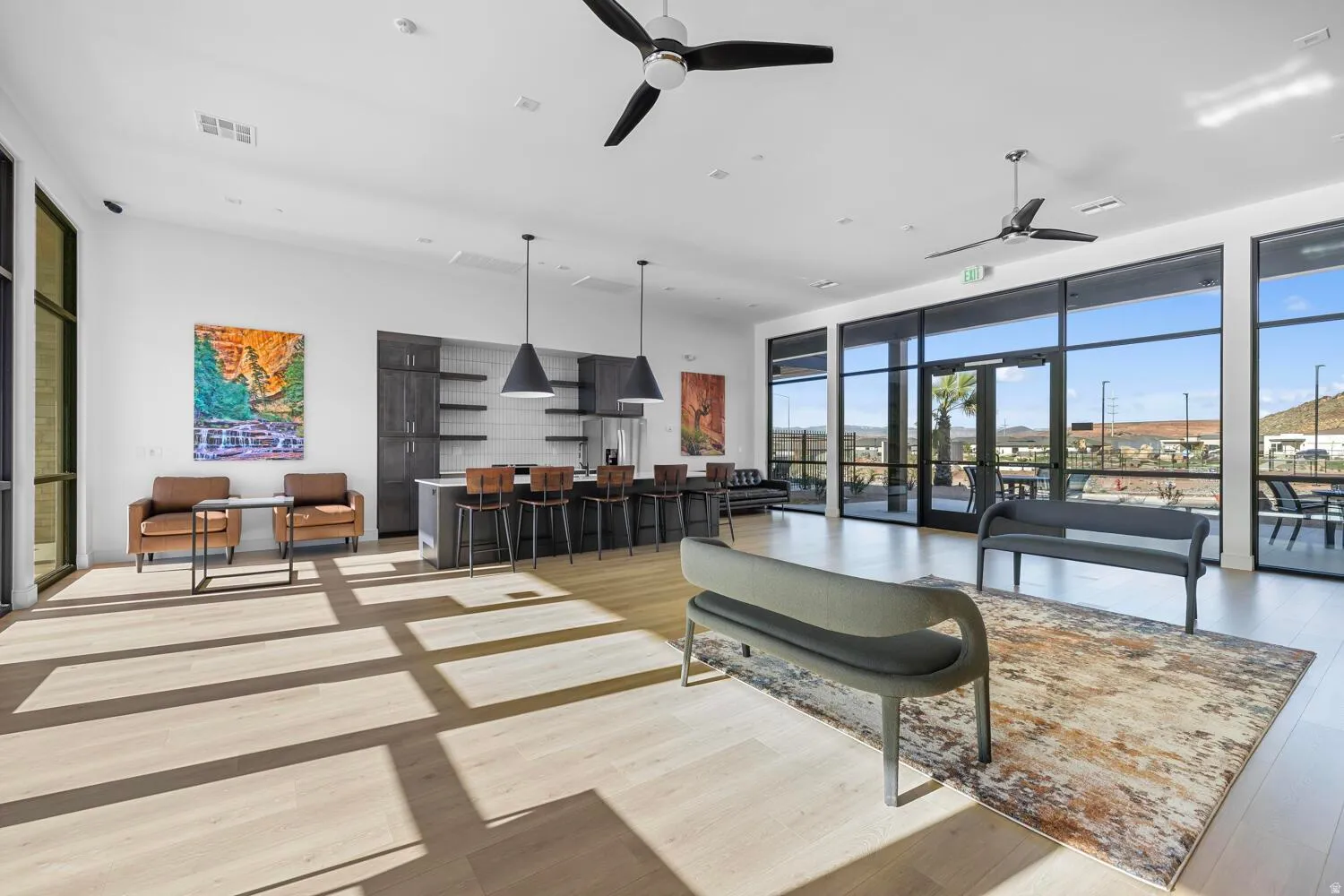 Open concept space featuring light wood-finish flooring, a built-in kitchen with shelving, pendant lighting, and full-height windows
