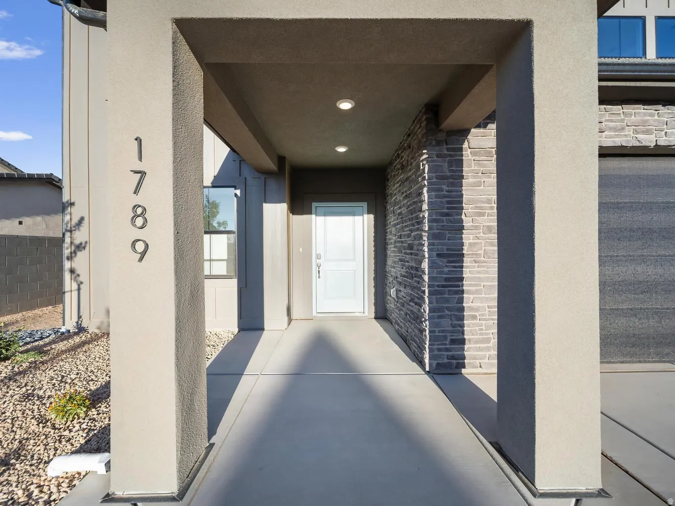 Covered entry with recessed lighting, stone veneer accent wall, modern house numbers, and a light-colored entry door
