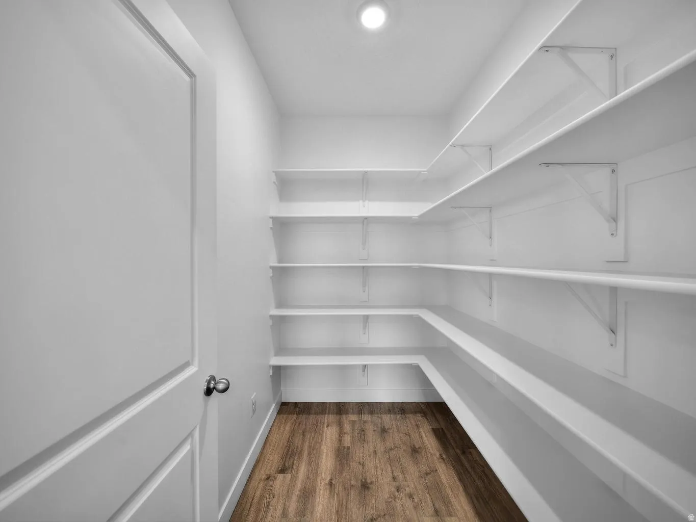 Walk-in pantry featuring extensive white shelving, recessed lighting, and wood-finish flooring