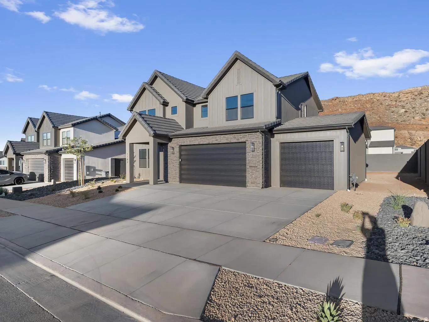 Modern exterior with board and batten siding, stone accents, and a dual garage