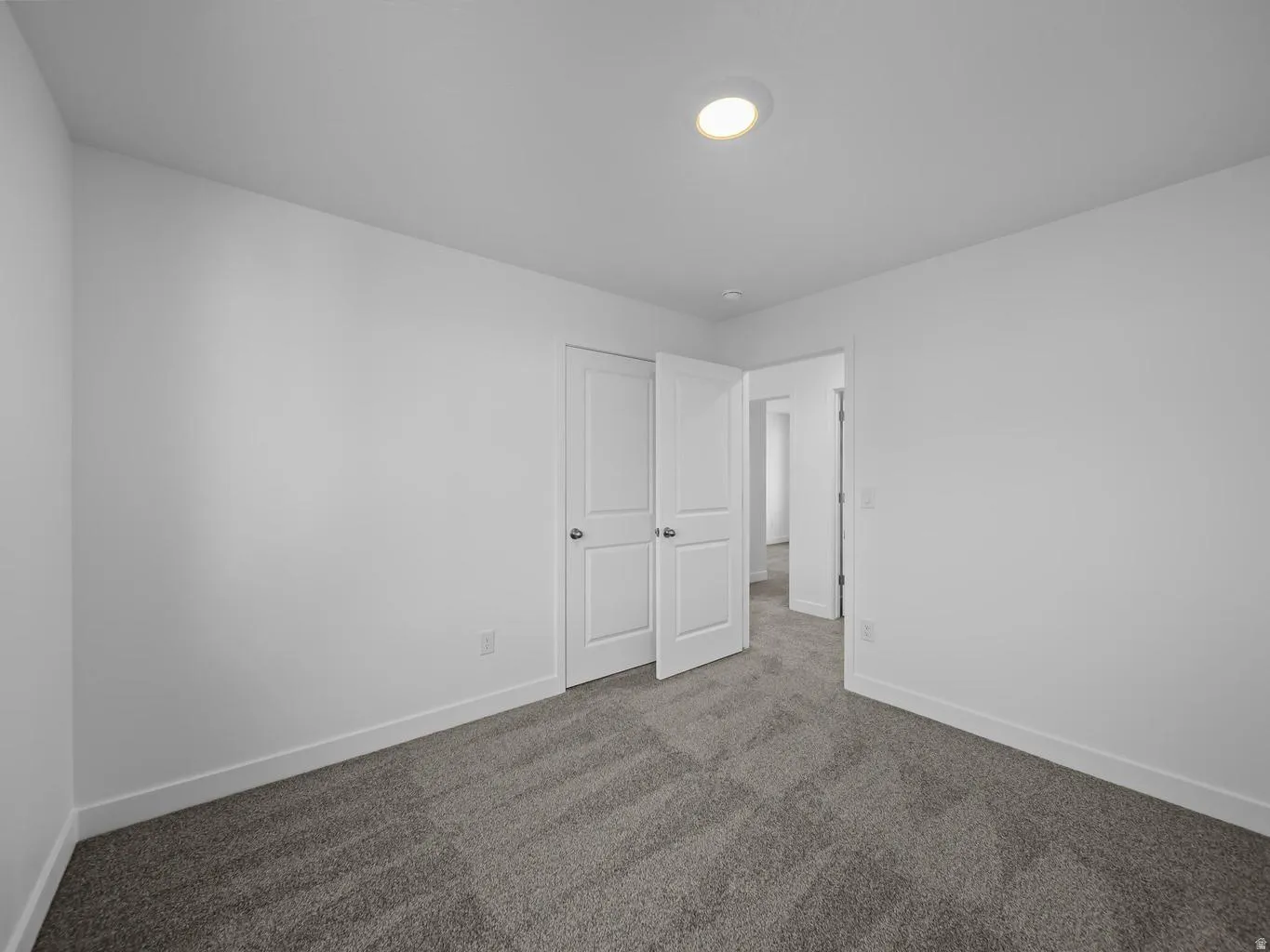 Recessed lighting illuminates the room, featuring plush gray carpeting and white interior doors