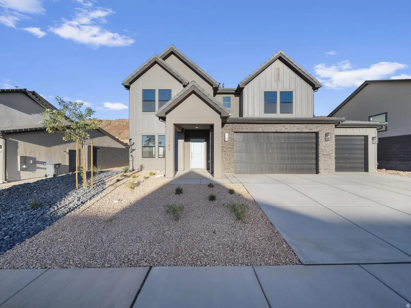 Two-story residence featuring a covered entry, mixed-material facade with stone accents, and a multi-car garage
