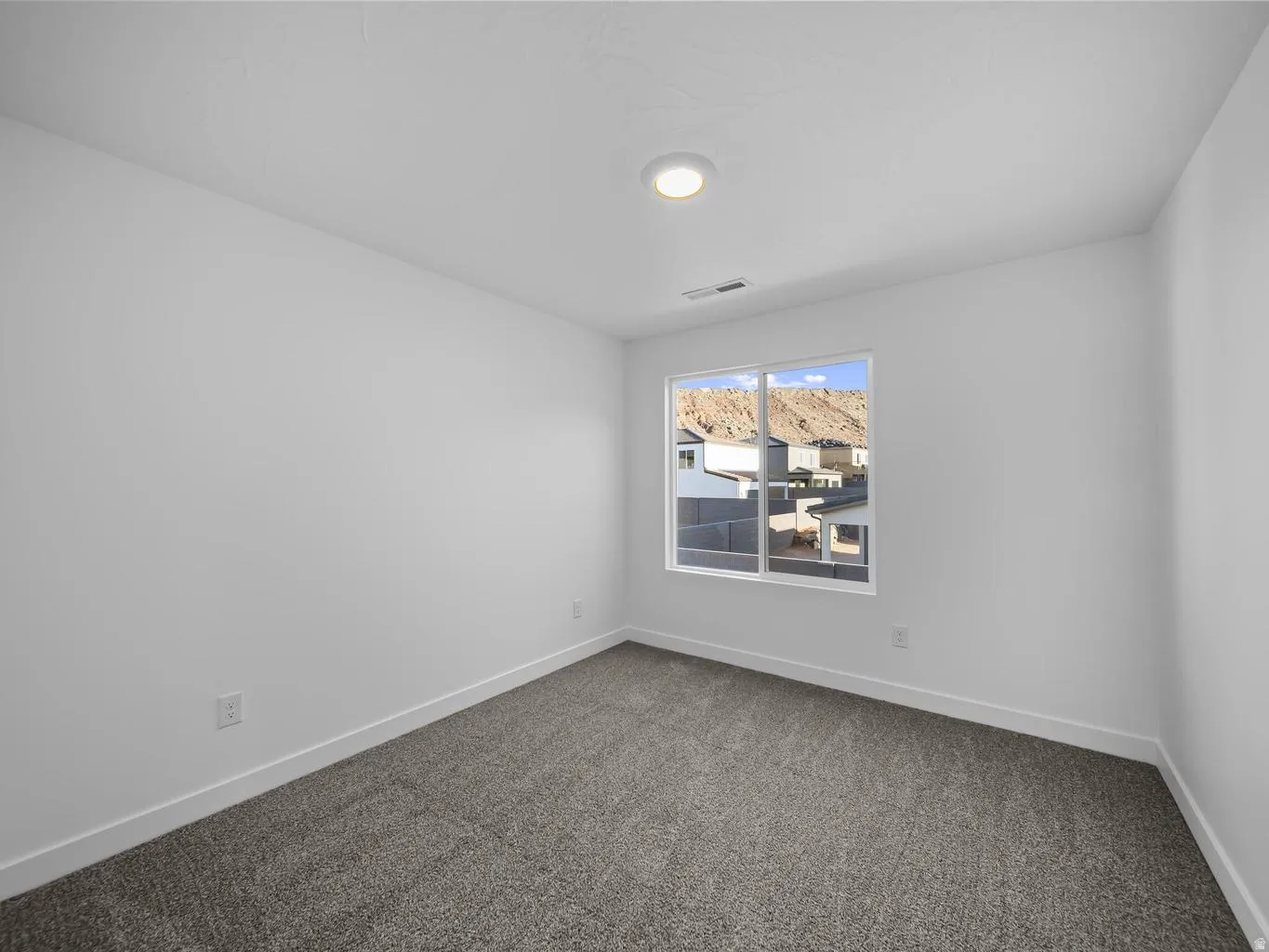 Neutral color palette with textured carpeting, a recessed ceiling light, and a window with mountain scenery