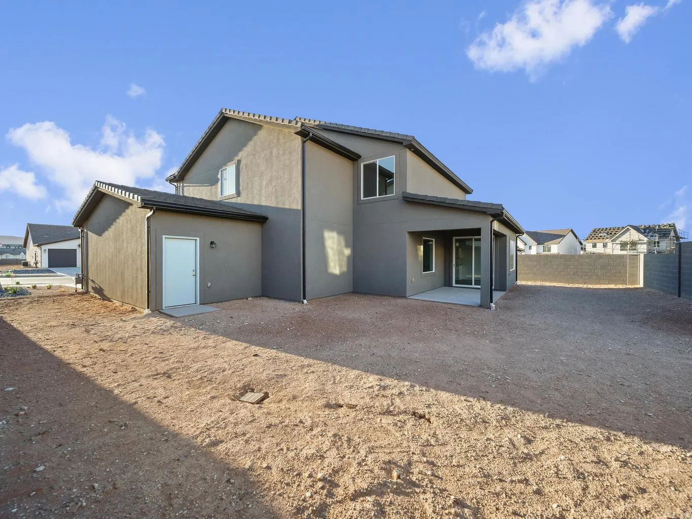 Stucco exterior with a covered patio, sliding glass door, and an exterior side door