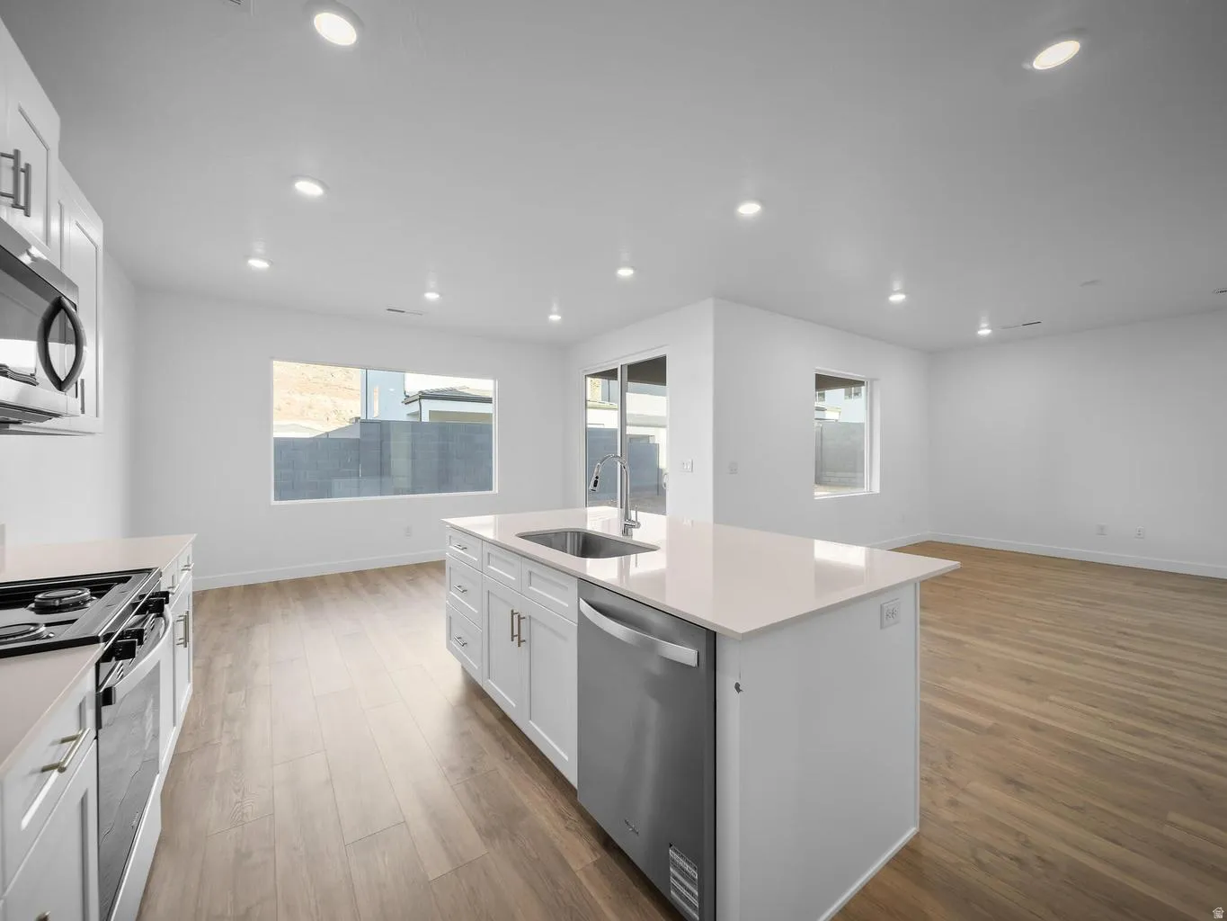 Kitchen featuring white cabinetry, a kitchen island with sink, stainless steel appliances, and wood-finish flooring