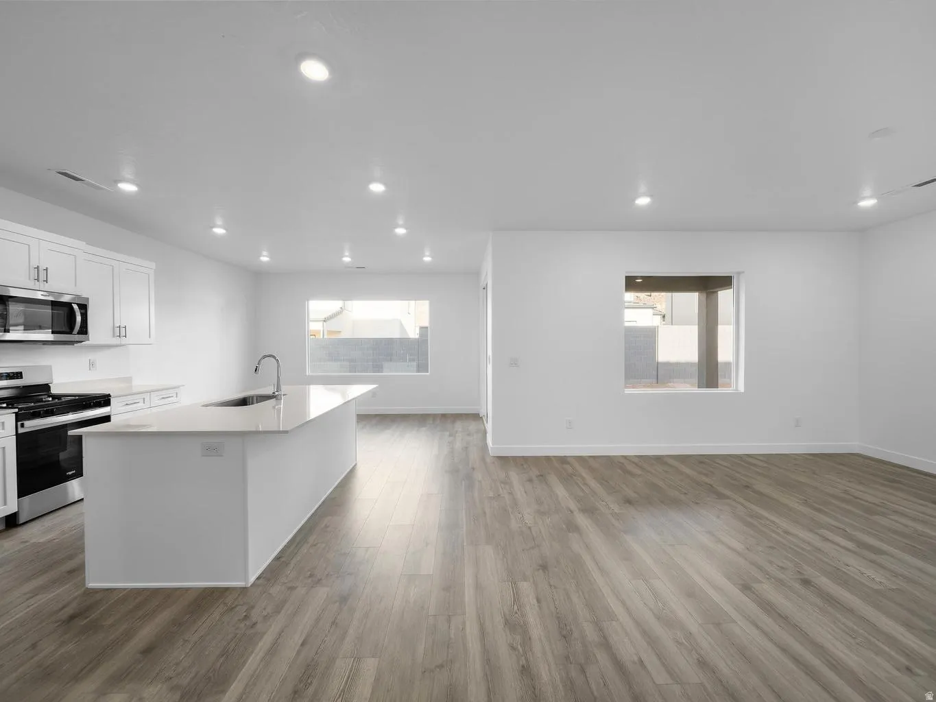 Kitchen with white cabinetry, stainless steel appliances, and a central island with an integrated sink