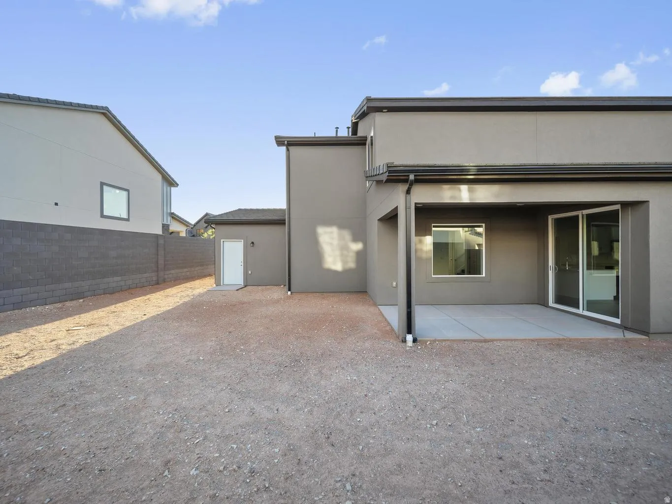 Covered patio with a concrete slab, sliding glass door, and exterior window