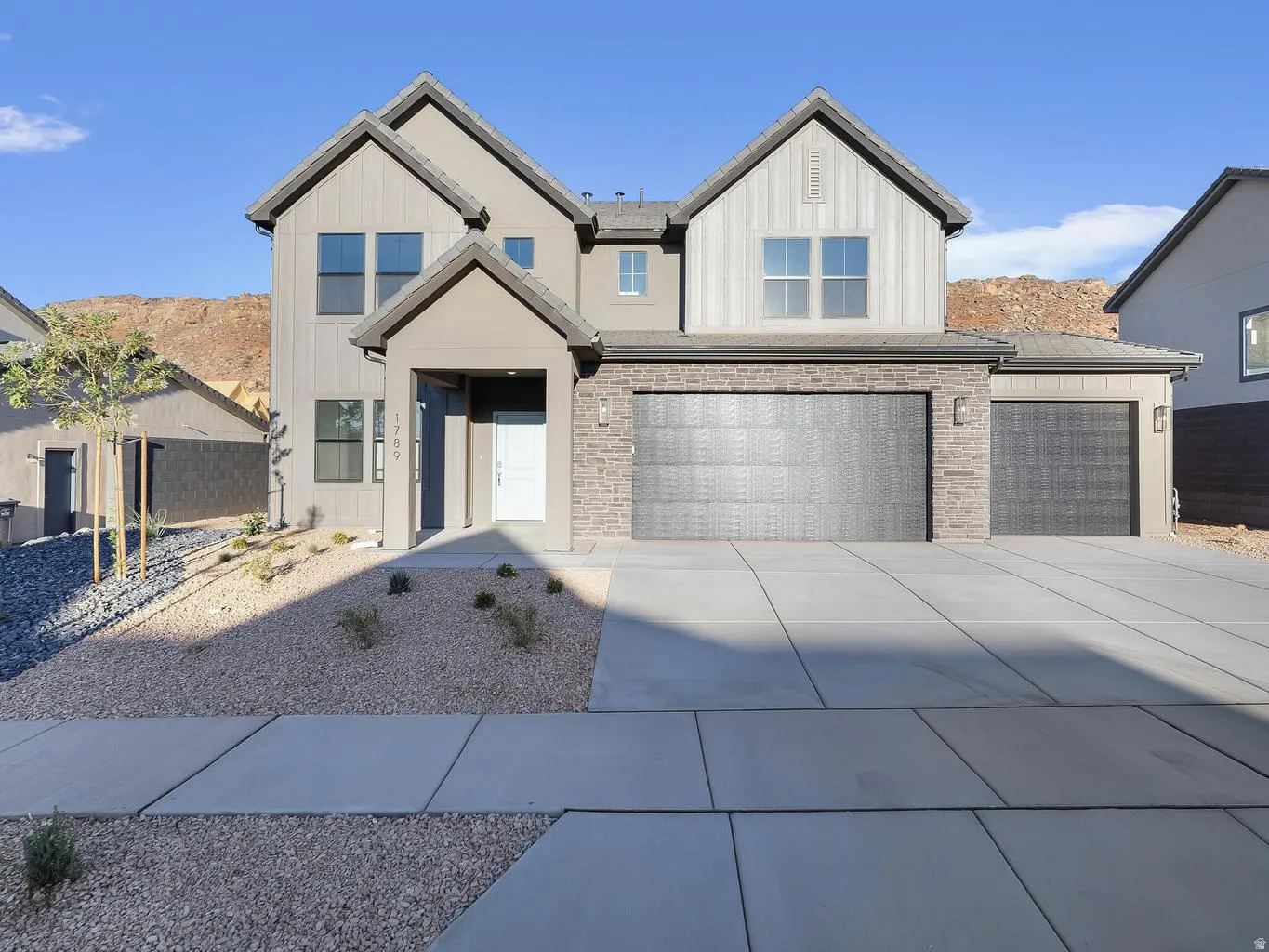 Two-story property featuring a multi-gable roofline, a two-car garage with textured doors, and a covered entry
