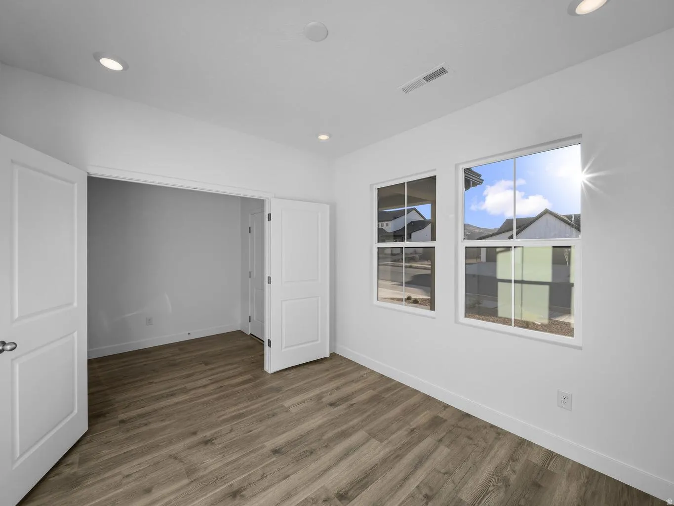 Wood-finish flooring, recessed lighting, white walls, and two large windows with grid patterns