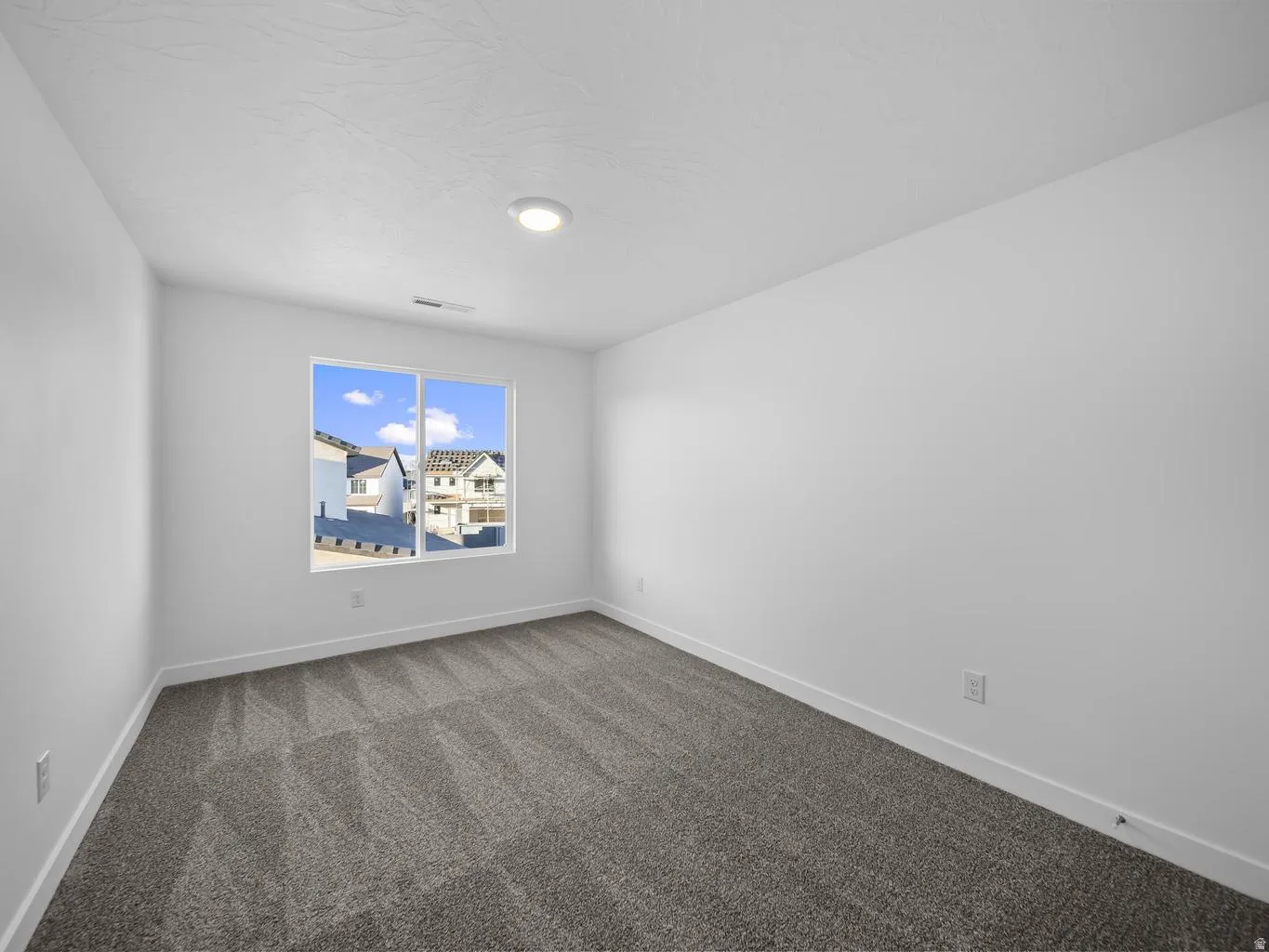 Neutral wall paint, textured ceiling finish, recessed ceiling light, window, and patterned carpet flooring