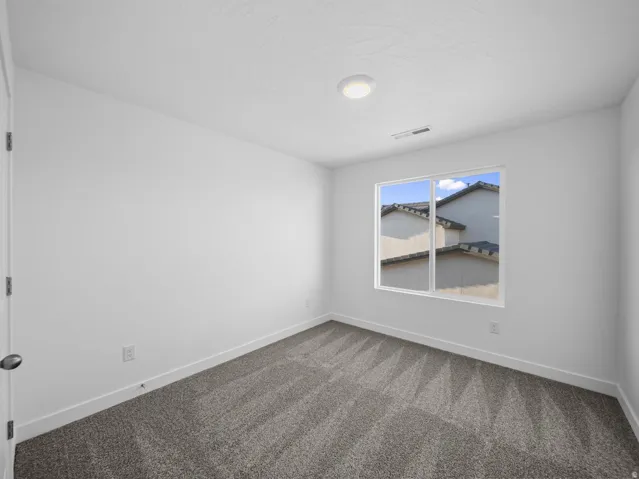 White walls, gray patterned carpet, and a flush-mount ceiling light