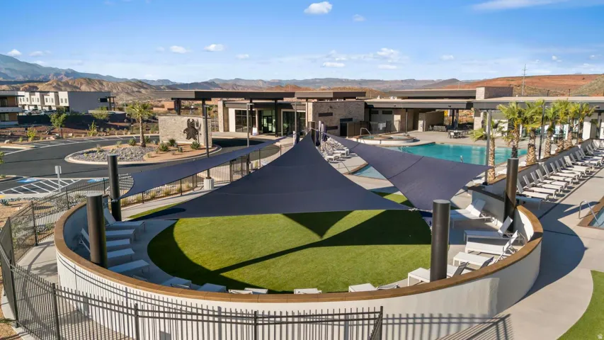 Community recreation area featuring a swimming pool, multiple shade sails, and an amphitheater-style lawn
