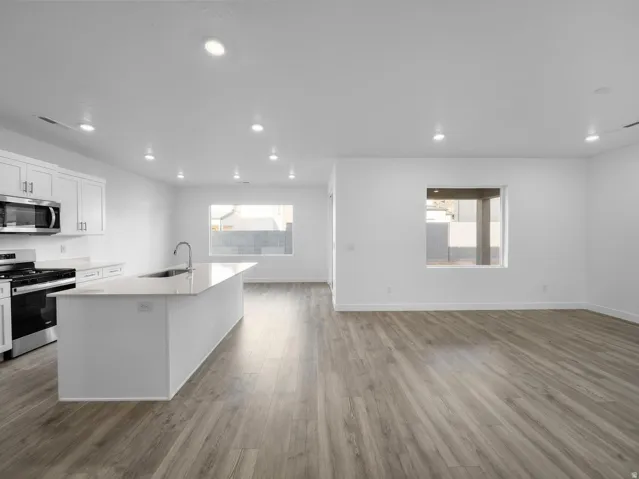 Kitchen with white cabinetry, stainless steel appliances, and a central island with an integrated sink