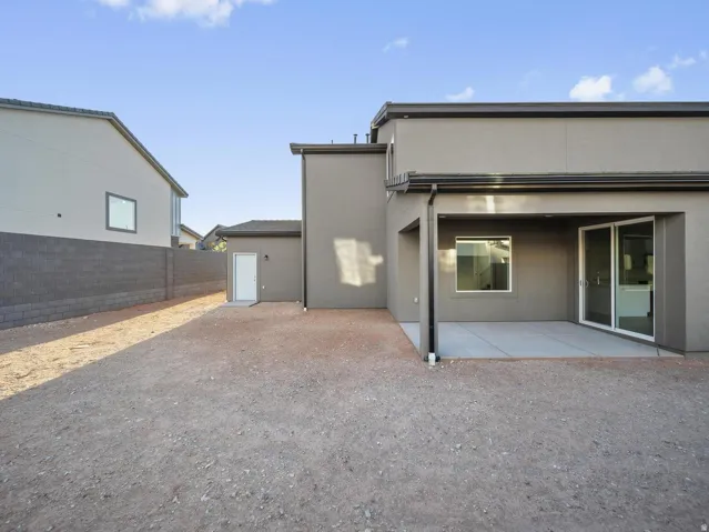 Covered patio with a concrete slab, sliding glass door, and exterior window