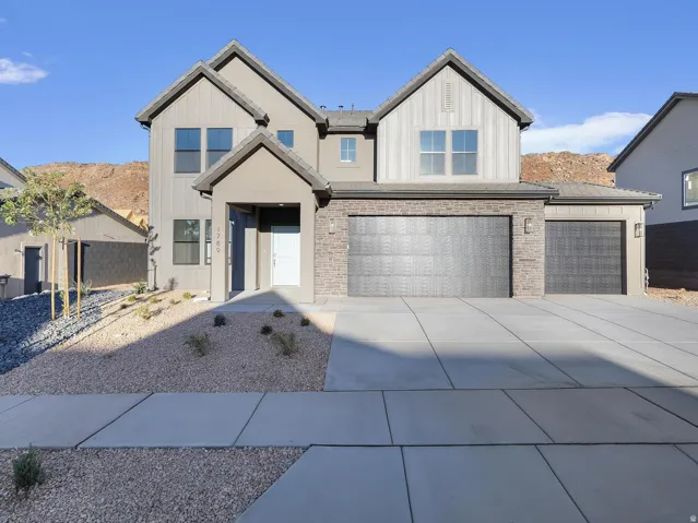 Two-story property featuring a multi-gable roofline, a two-car garage with textured doors, and a covered entry