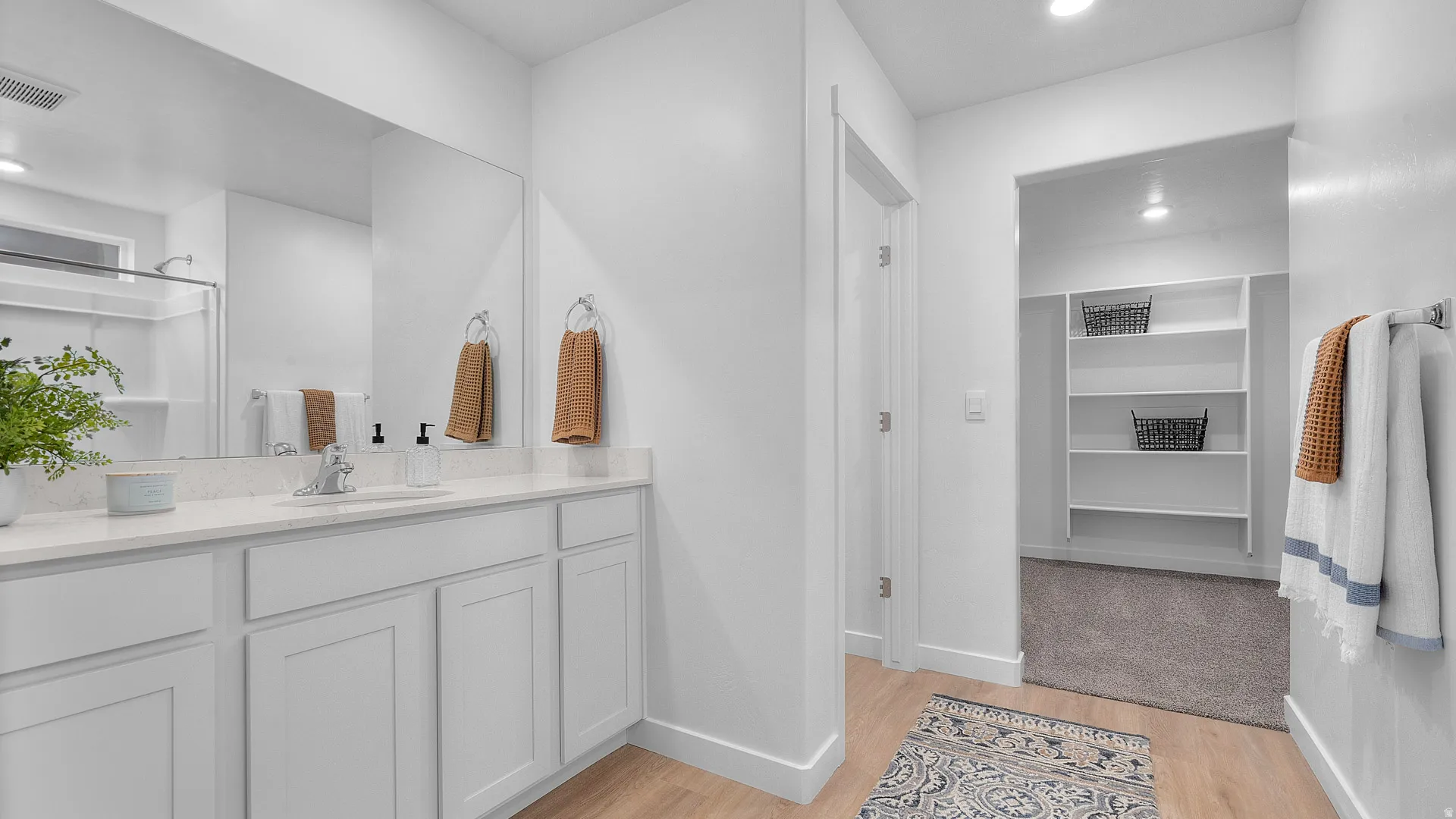 Bathroom featuring a single vanity with light-toned countertop, integrated sink, and white cabinetry