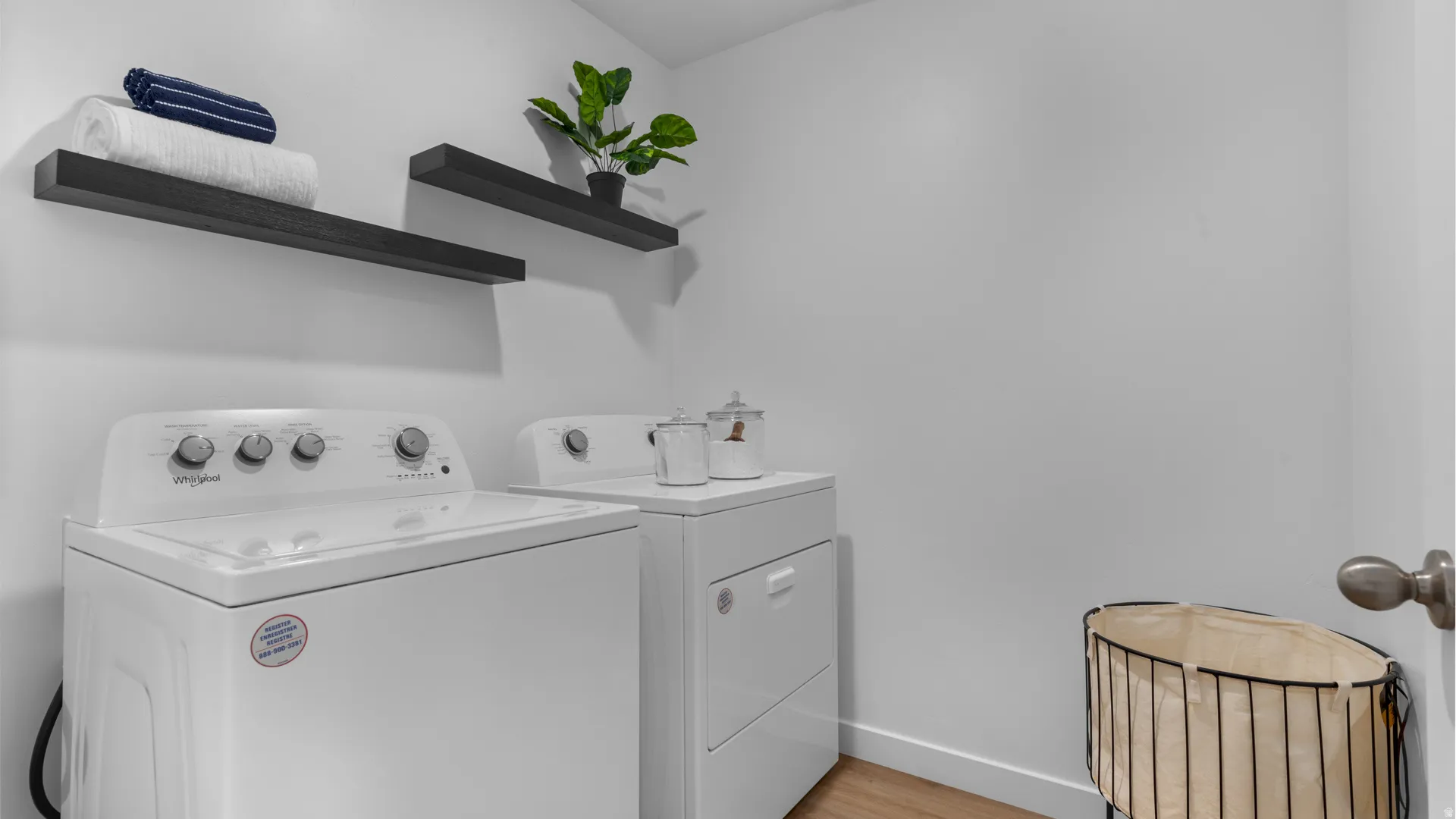 Laundry area with two floating shelves and wood-finish flooring