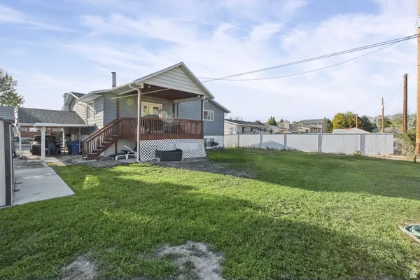Expansive rear yard with a covered patio, wood deck with stairs, carport
