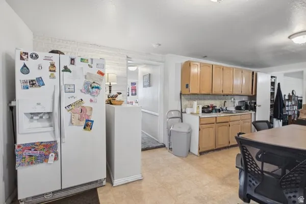 Kitchen area with light wood-finish cabinetry, a utility sink, and tile flooring