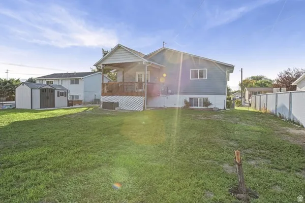 Expansive grassy backyard featuring a covered deck, attached outdoor storage shed