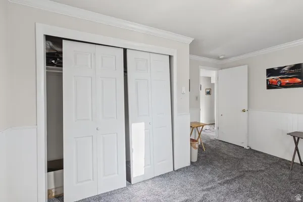 Wall-to-wall carpeting and white wainscoting with crown molding
