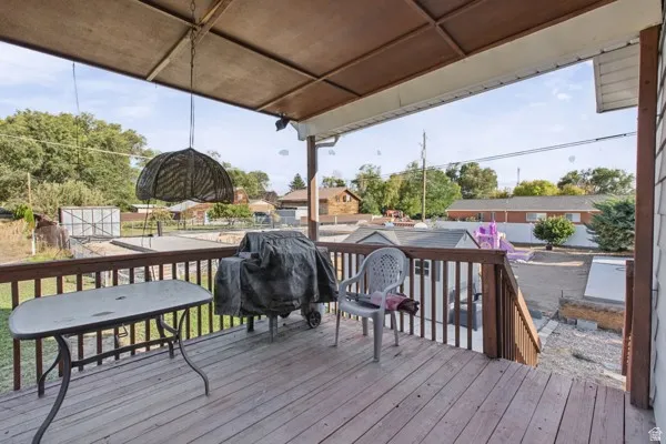 Covered wooden deck with railing, stairs, and a built-in outdoor light fixture