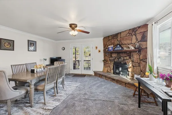 Floor-to-ceiling stone fireplace, ceiling fan with integrated lighting, white trim molding and French doors