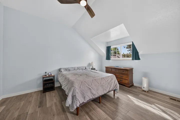 Room with sloped ceilings, wood-finish flooring, and a ceiling fan