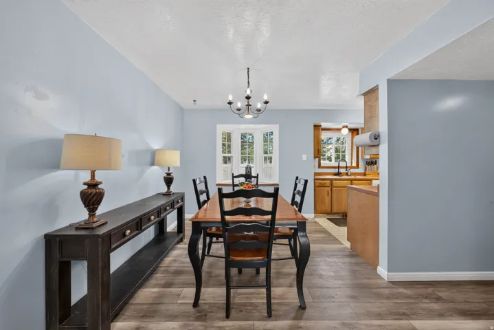 Wood-finish flooring, light blue wall paint, and a black chandelier