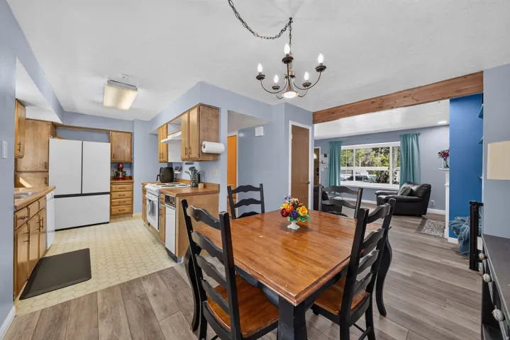 Open-concept living area featuring wood-finish flooring, a wood beam architectural detail, and a prominent window