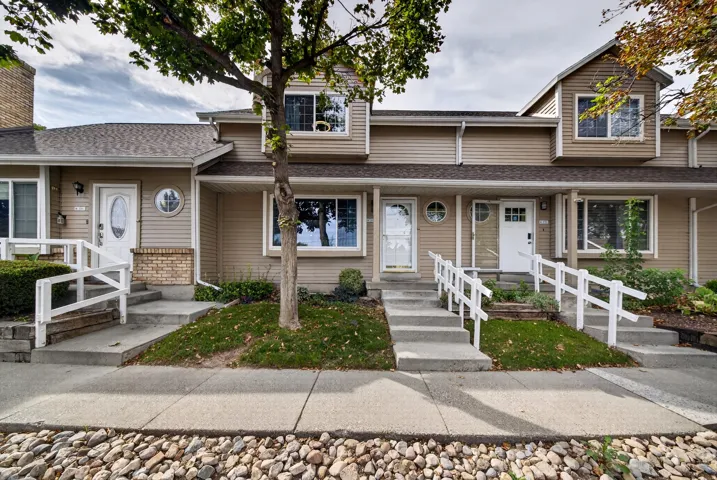 Townhome-style exterior with neutral-toned siding, asphalt shingle roofing, and multiple windows